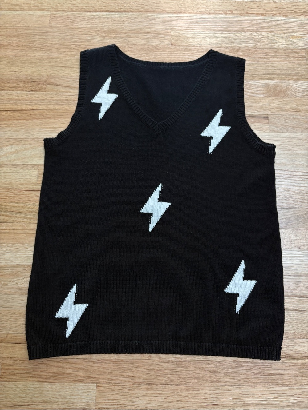 Black knit sweater vest featuring a V-neckline and white lightning bolt graphics